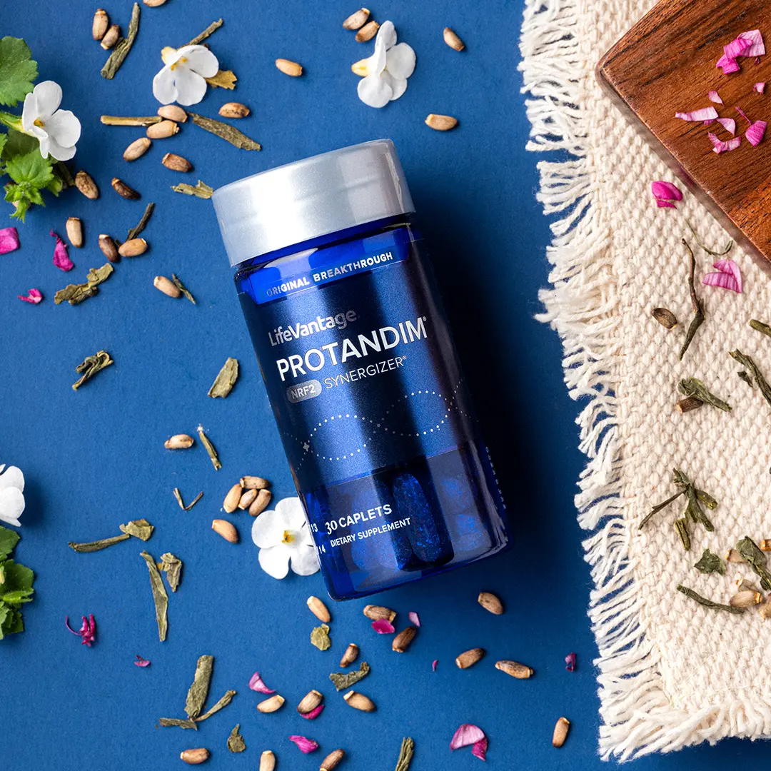 Protandim NRF2 bottle with natural elements on a blue background